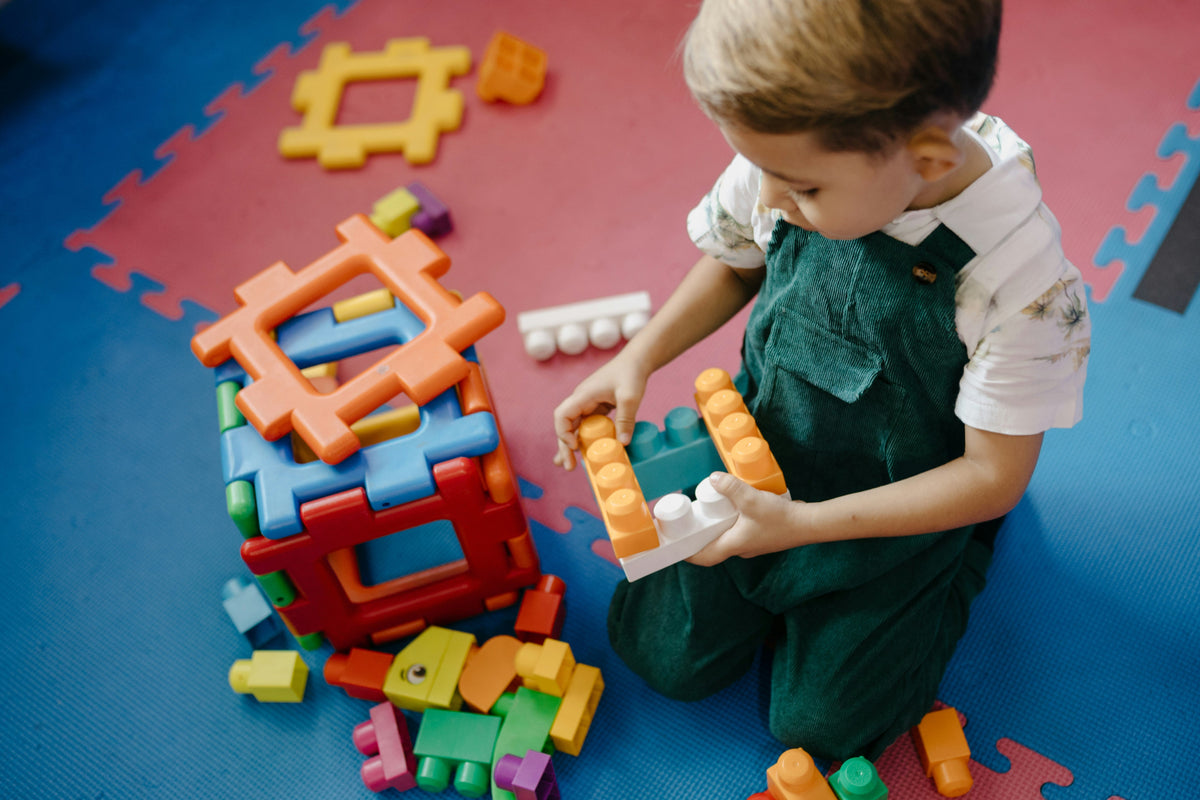 child playing with building blocks on floor creative play
