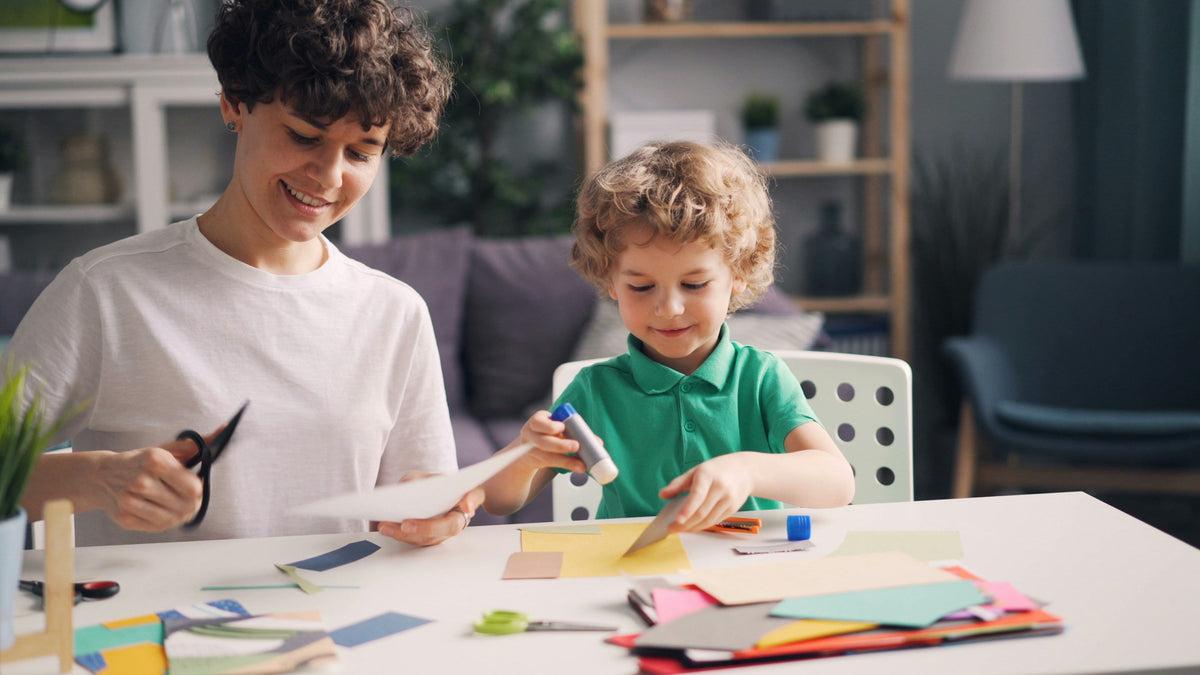 kids making arts and crafts project with paper, scissors, and paint
